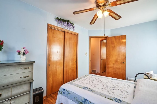 bedroom with ceiling fan, wood-type flooring, and a closet