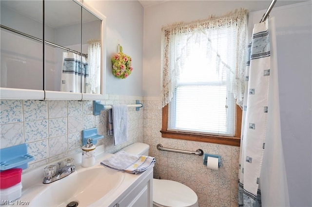 bathroom with a wealth of natural light, vanity, tile walls, and toilet