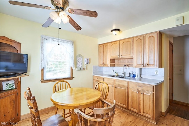 kitchen featuring decorative backsplash, light hardwood / wood-style flooring, ceiling fan, and sink