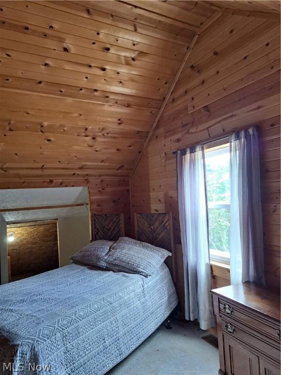 carpeted bedroom with wooden walls, wood ceiling, and vaulted ceiling