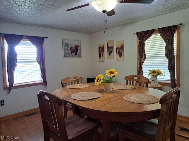 dining area with hardwood / wood-style flooring, ceiling fan, and a textured ceiling