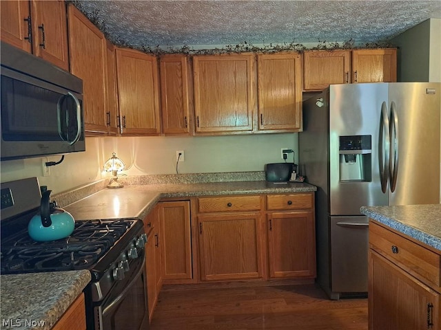 kitchen featuring a textured ceiling, dark hardwood / wood-style flooring, and stainless steel appliances