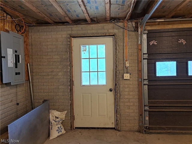 entryway with concrete floors, electric panel, and brick wall