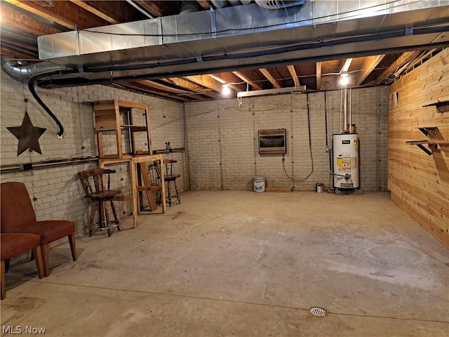 basement featuring water heater and brick wall