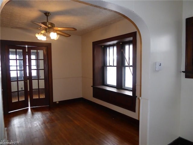 empty room with ceiling fan, french doors, dark hardwood / wood-style floors, plenty of natural light, and a textured ceiling