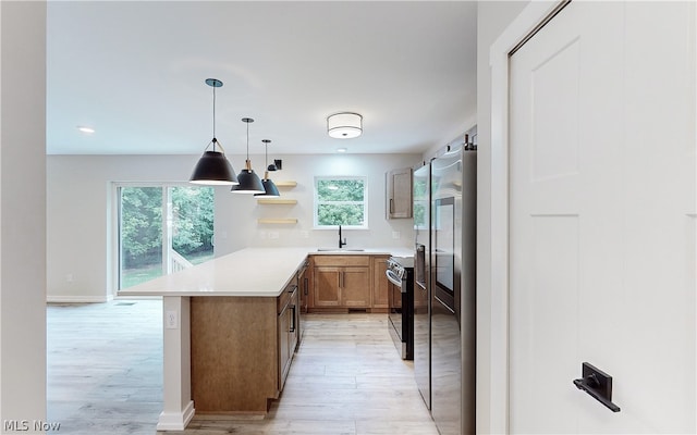 kitchen featuring sink, stainless steel fridge, kitchen peninsula, and a healthy amount of sunlight