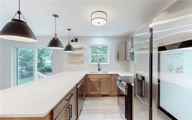 kitchen with sink, stainless steel appliances, a wealth of natural light, and decorative light fixtures