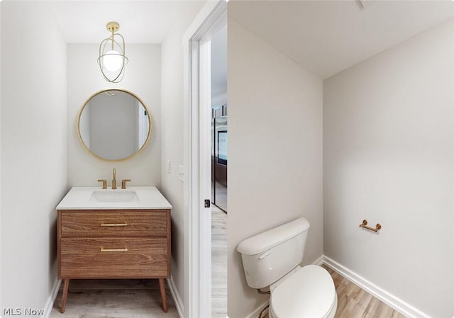 bathroom with vanity, toilet, and hardwood / wood-style floors