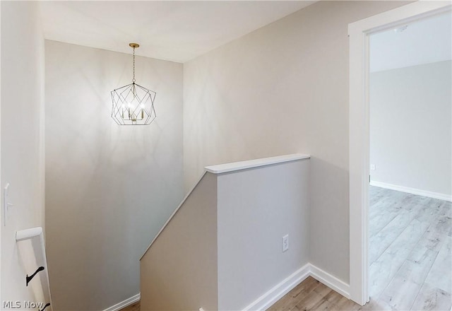 stairs with wood-type flooring and a chandelier