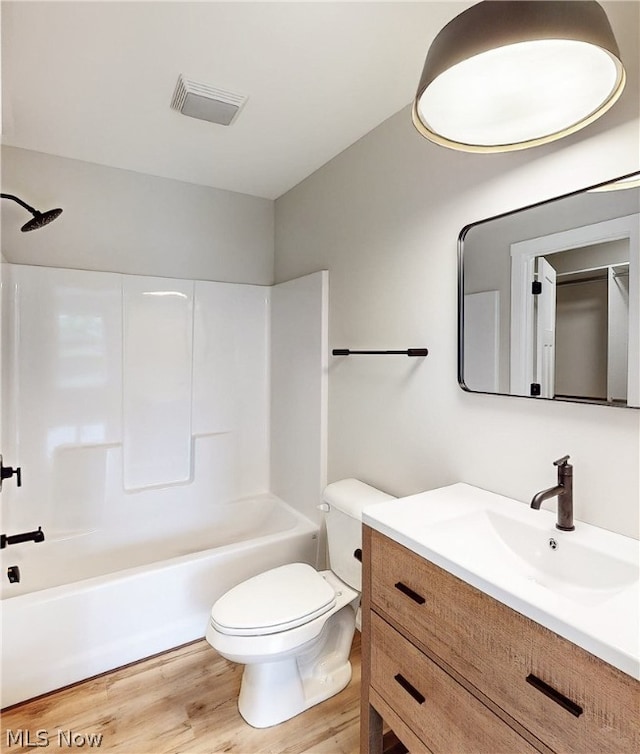 full bathroom featuring hardwood / wood-style flooring, toilet, bathing tub / shower combination, and vanity