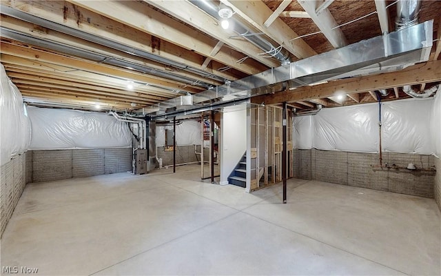 basement featuring heating unit and brick wall