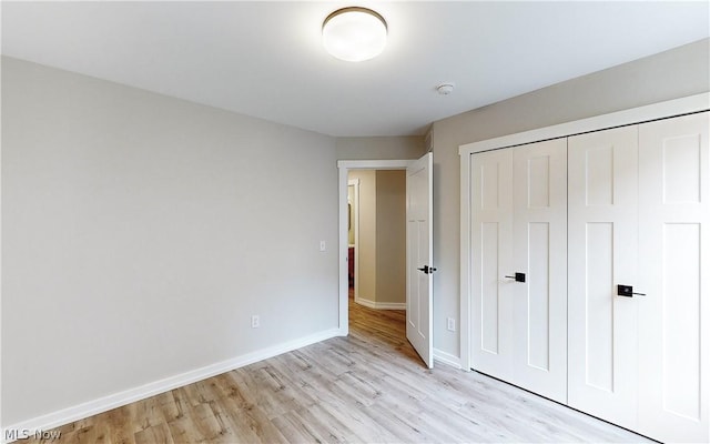 unfurnished bedroom with light hardwood / wood-style flooring and a closet