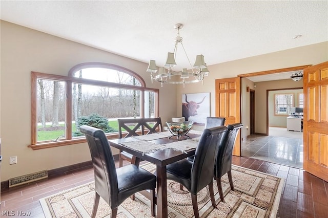 dining area with an inviting chandelier, wood-type flooring, and a textured ceiling