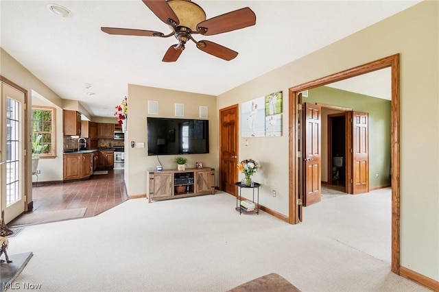 carpeted living room with ceiling fan and sink