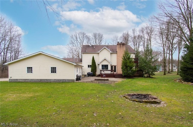 rear view of property with a fire pit, a patio area, and a lawn