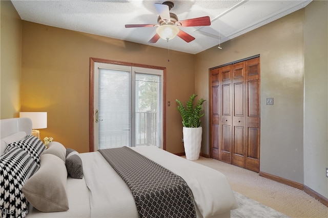 carpeted bedroom with ceiling fan, a textured ceiling, and a closet