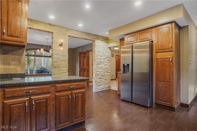 kitchen featuring decorative backsplash, dark hardwood / wood-style floors, stainless steel fridge, and dark stone countertops