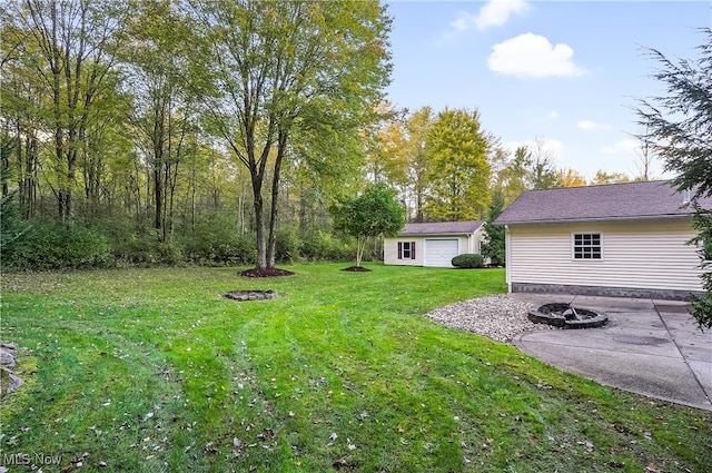 view of yard featuring a garage, a fire pit, and an outbuilding