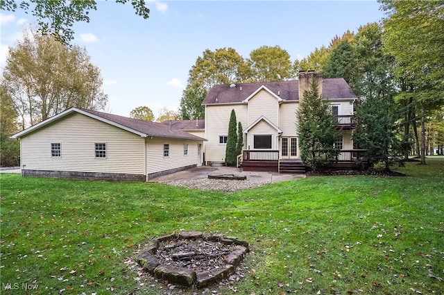 back of property with an outdoor fire pit, a yard, and a wooden deck