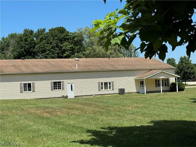 back of house featuring central AC unit and a lawn