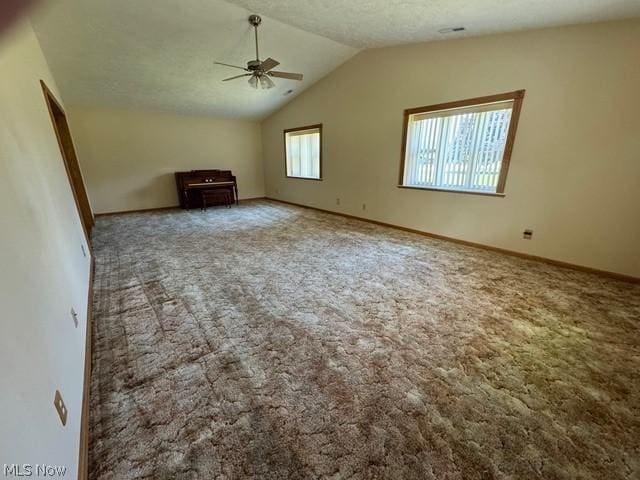 unfurnished living room featuring ceiling fan, lofted ceiling, carpet floors, and a textured ceiling