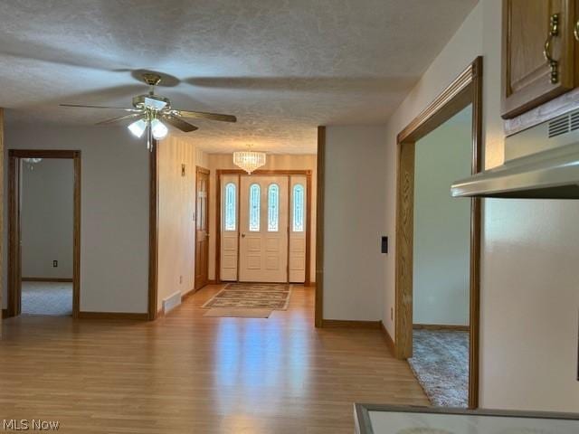 entrance foyer with ceiling fan with notable chandelier, a textured ceiling, and light hardwood / wood-style floors