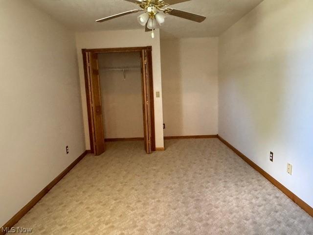 unfurnished bedroom with light colored carpet, ceiling fan, and a closet