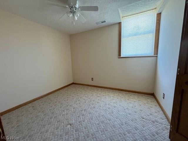 carpeted empty room featuring ceiling fan and a textured ceiling