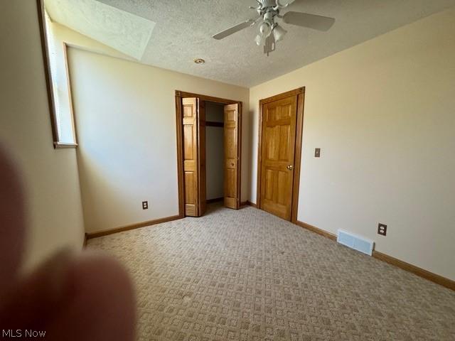 unfurnished bedroom with ceiling fan, a closet, carpet flooring, and a textured ceiling