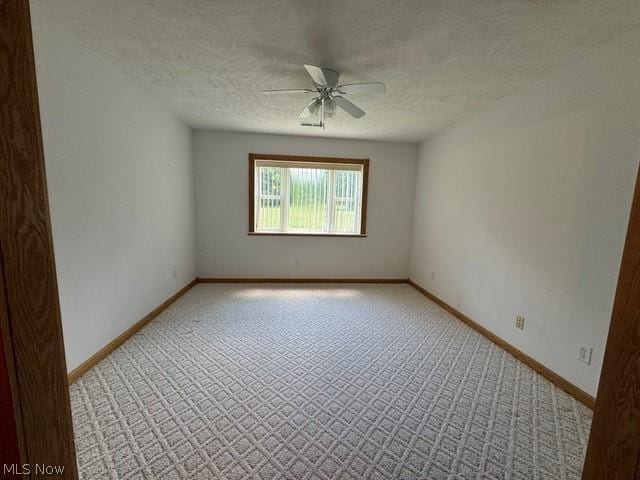 spare room with ceiling fan, light colored carpet, and a textured ceiling