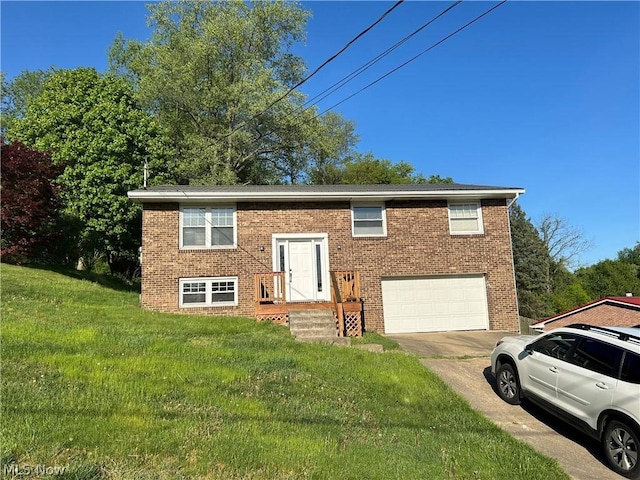 bi-level home featuring an attached garage, brick siding, concrete driveway, and a front yard