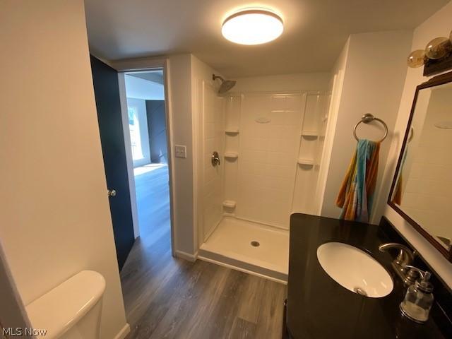 bathroom with a shower, hardwood / wood-style floors, vanity, and toilet