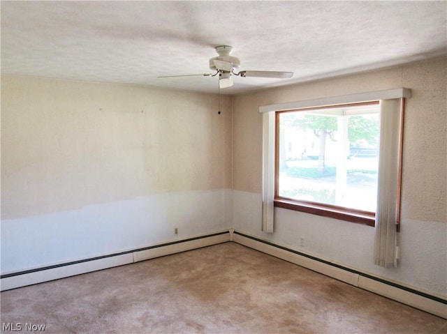 carpeted empty room featuring ceiling fan and baseboard heating