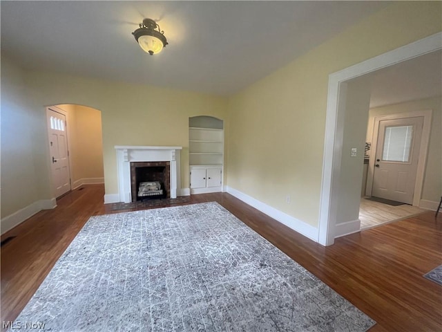 unfurnished living room featuring dark hardwood / wood-style flooring and built in shelves