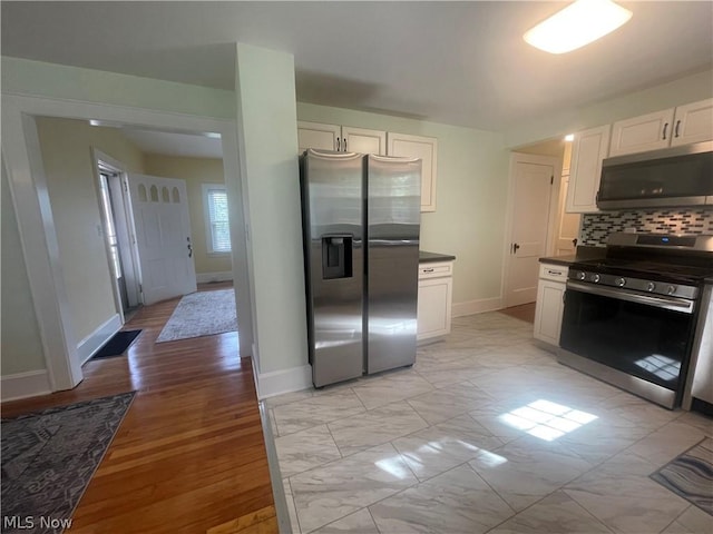 kitchen featuring stainless steel appliances, white cabinets, and decorative backsplash