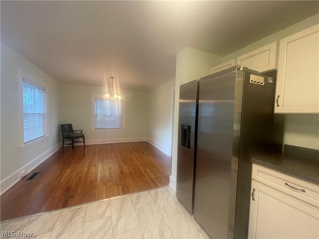 kitchen with white cabinetry, pendant lighting, stainless steel fridge, and light hardwood / wood-style floors