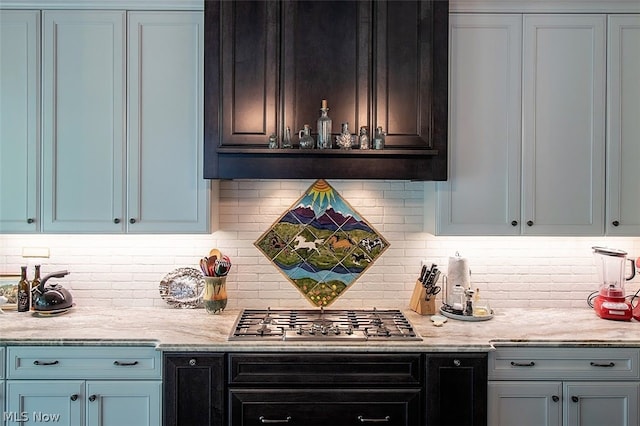 bar featuring stainless steel gas stovetop, backsplash, and light stone counters