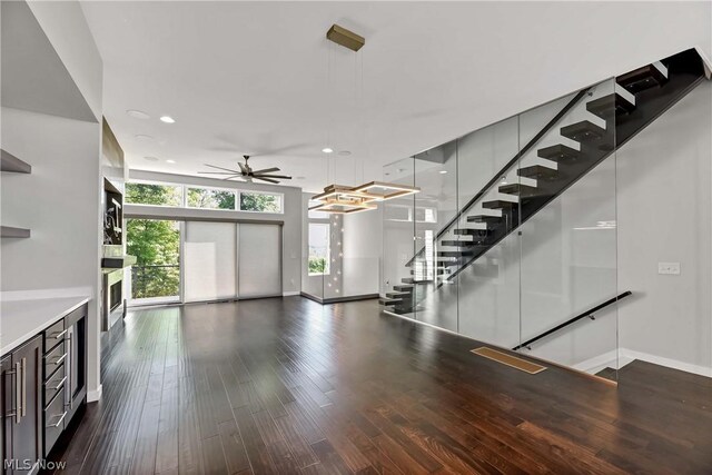 unfurnished living room featuring ceiling fan and dark hardwood / wood-style flooring