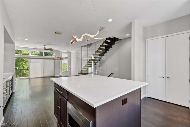 kitchen featuring dark brown cabinetry, a center island, ceiling fan, and dark wood-type flooring