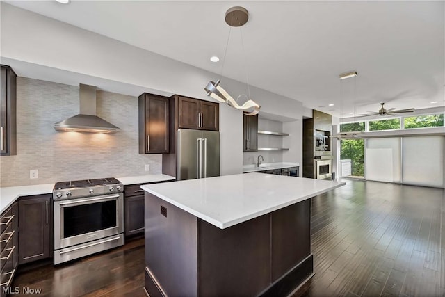 kitchen featuring dark hardwood / wood-style floors, tasteful backsplash, wall chimney exhaust hood, high quality appliances, and pendant lighting