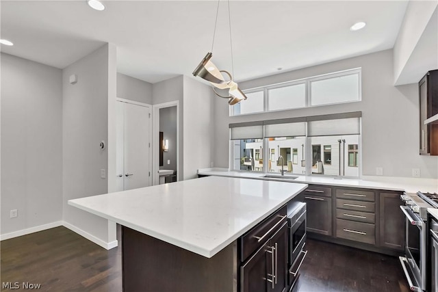 kitchen featuring sink, pendant lighting, stainless steel stove, and dark hardwood / wood-style flooring