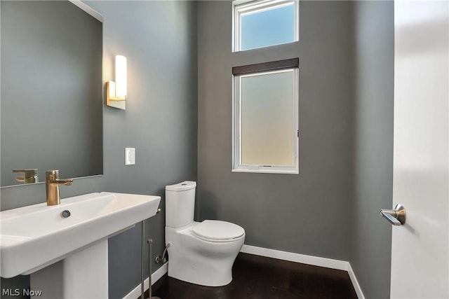 bathroom with plenty of natural light, toilet, sink, and wood-type flooring