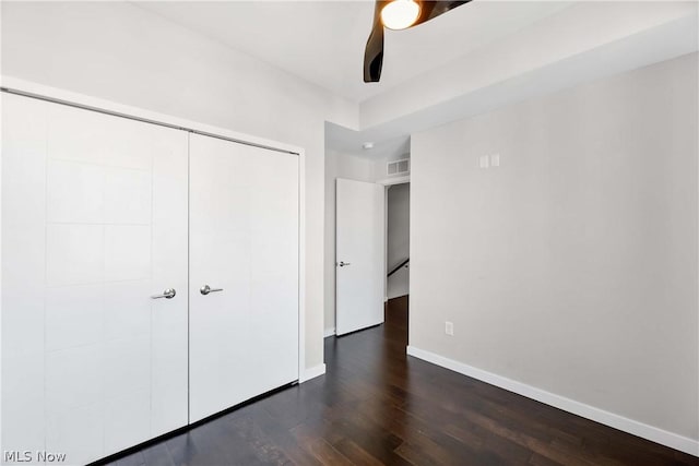 unfurnished bedroom featuring dark wood-type flooring, ceiling fan, and a closet