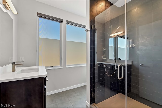 bathroom featuring a healthy amount of sunlight, tile flooring, walk in shower, and vanity