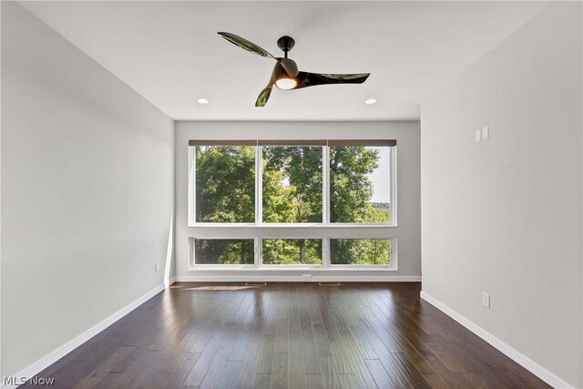 empty room with a wealth of natural light and dark hardwood / wood-style flooring