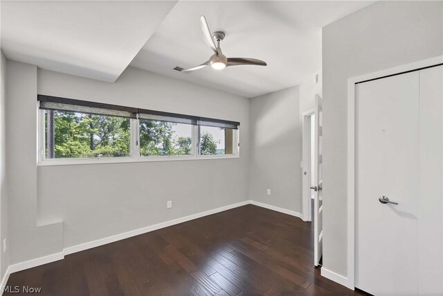 unfurnished bedroom with dark wood-type flooring, a closet, and ceiling fan