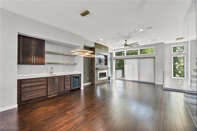 unfurnished living room featuring wine cooler, sink, ceiling fan, and dark hardwood / wood-style floors