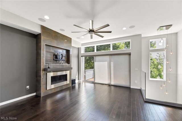 unfurnished living room featuring ceiling fan, a fireplace, and dark hardwood / wood-style floors