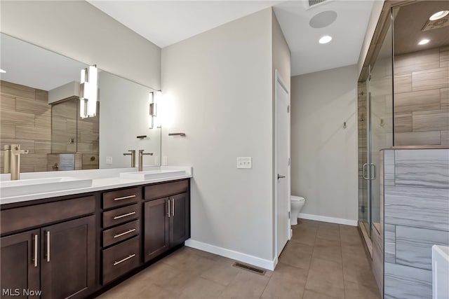 bathroom with a shower with shower door, dual bowl vanity, toilet, and tile floors