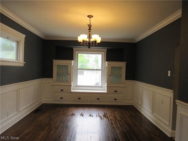 unfurnished dining area with dark wood-type flooring, a chandelier, and ornamental molding